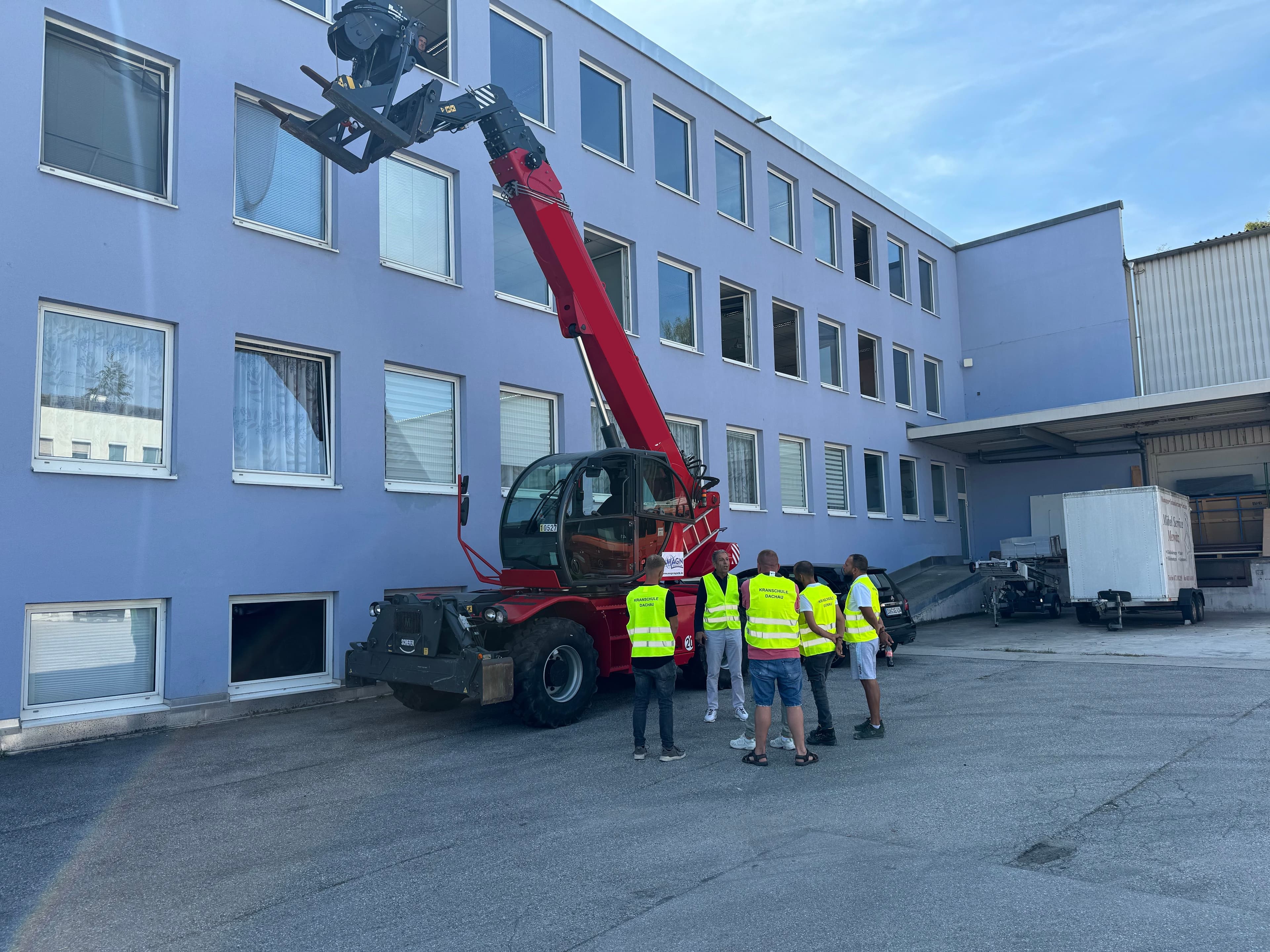 Teleskopstapler mit einer Gruppe, die die Technik erklärt bekommt