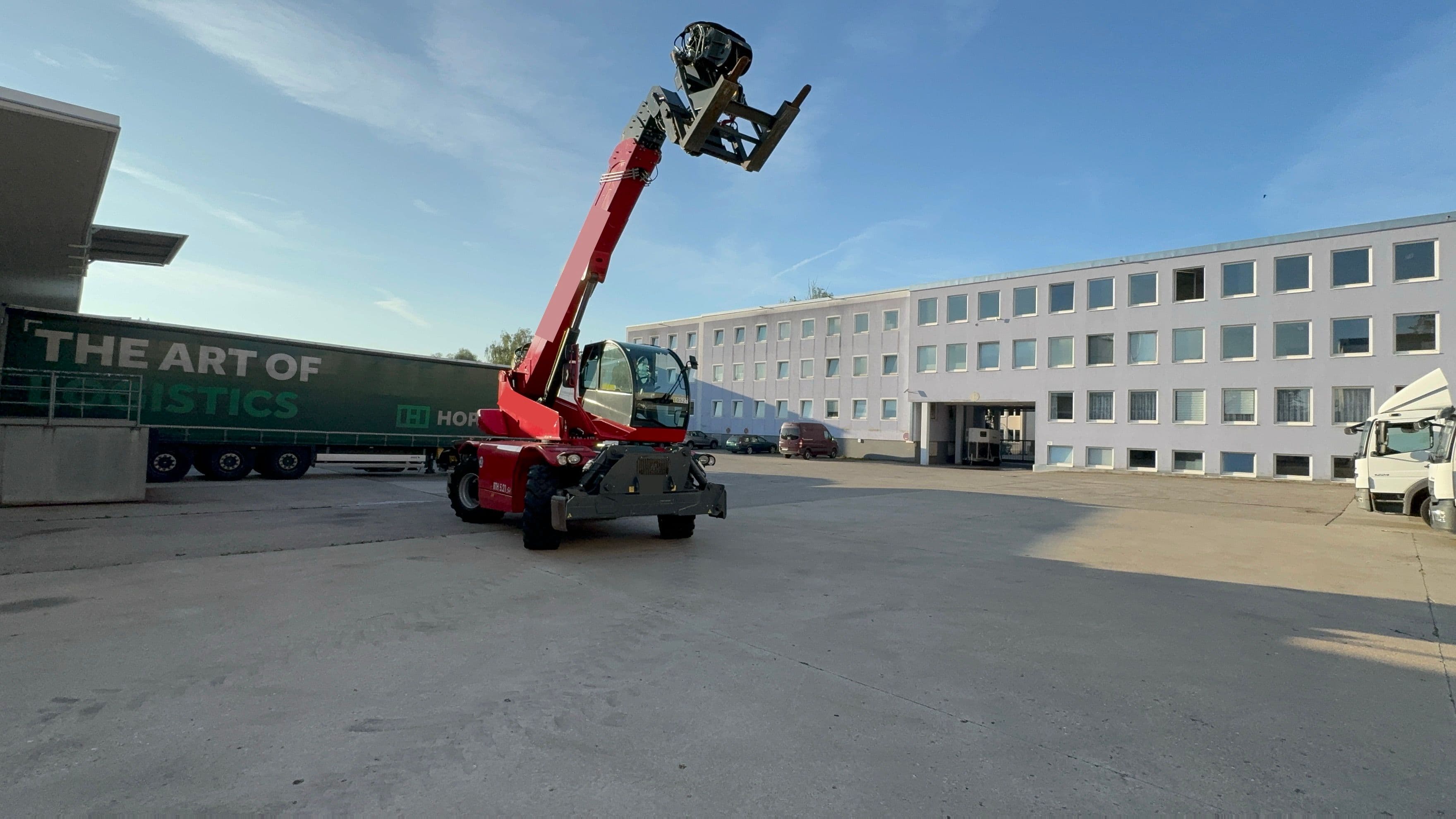 Roter Teleskopstapler hebt eine schwere Last auf einem Lagergelände.