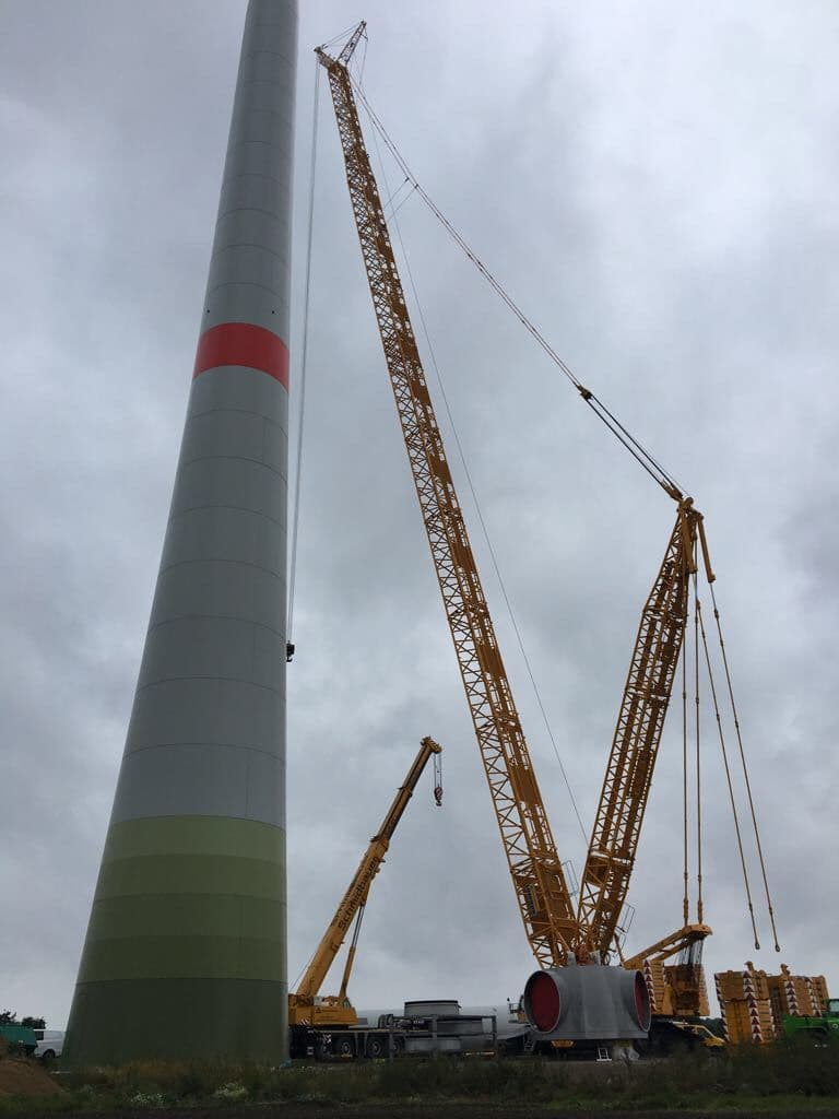 Raupenkran, der ein Windkraftwerk mit einem Hilfskran aufbaut.