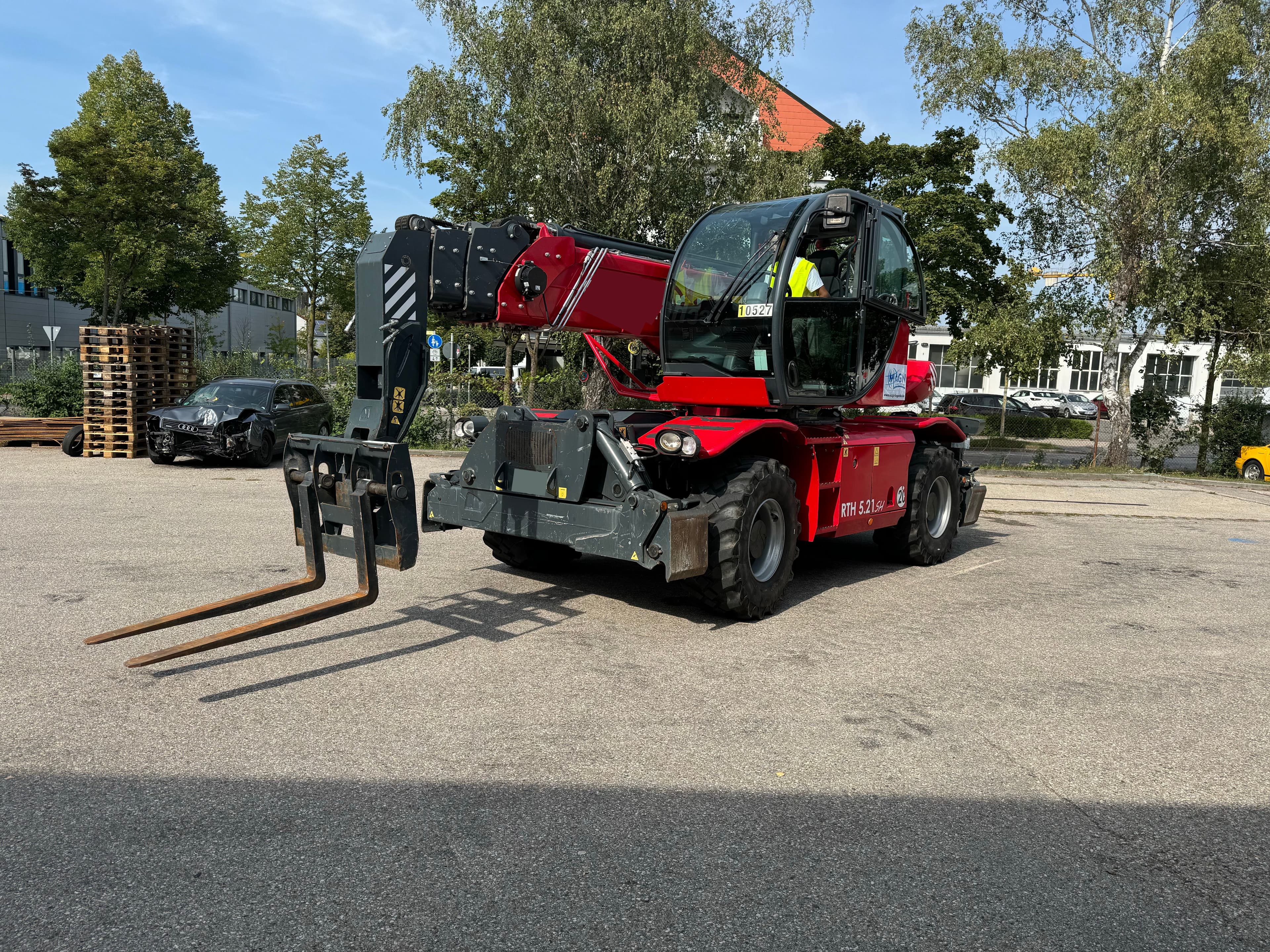 Roter Teleskopstapler mit montierten Gabeln während einer Schulung für Staplerführer.